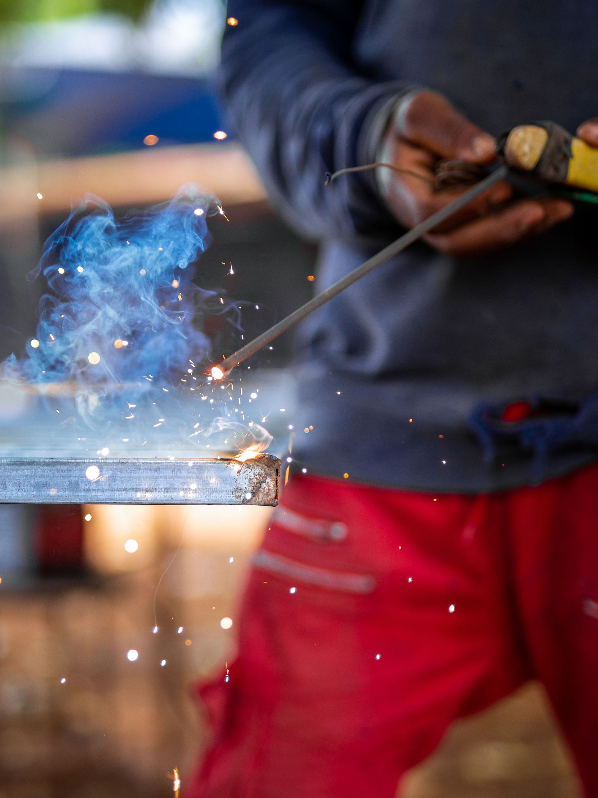 Close-up of a welder working on metal with visible sparks and smoke for industrial use.