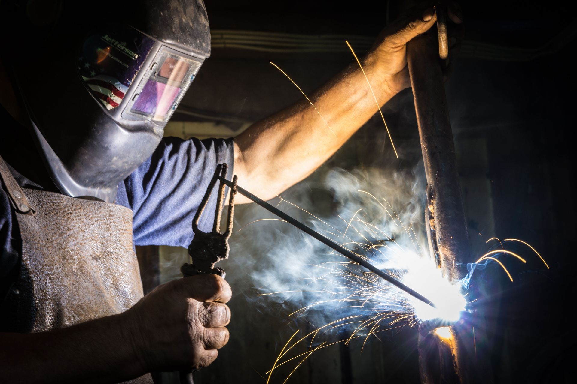 Close-up of a welder in action, showcasing bright sparks and metalworking skill indoors.